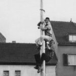 Peter Klug und ein Freund kletttern 1955 den Maibaum hoch in Dransdorf